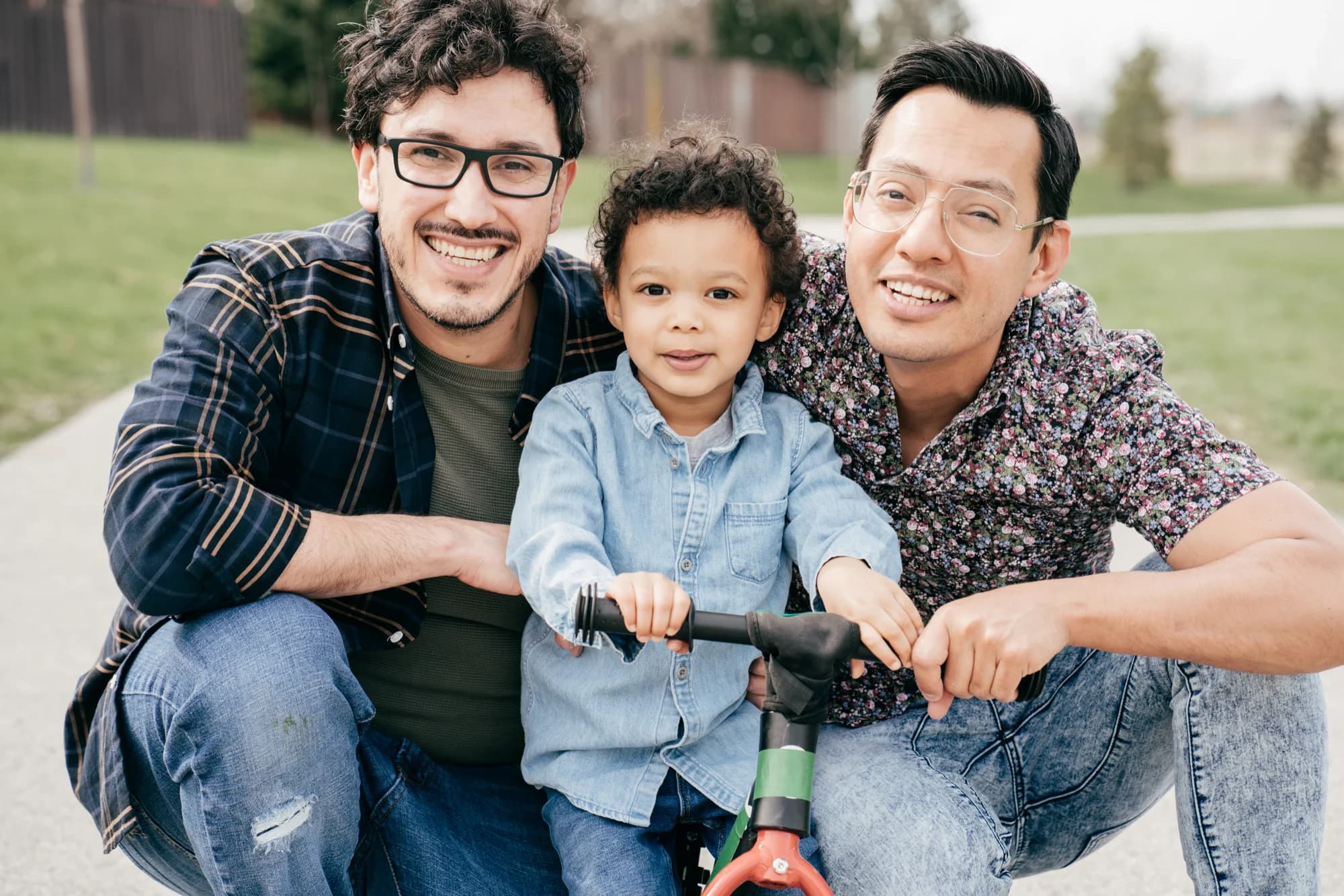 Two dads with child on tricycle